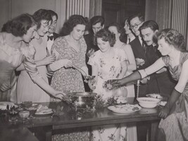 A woman ladling out drink to other partygoers.